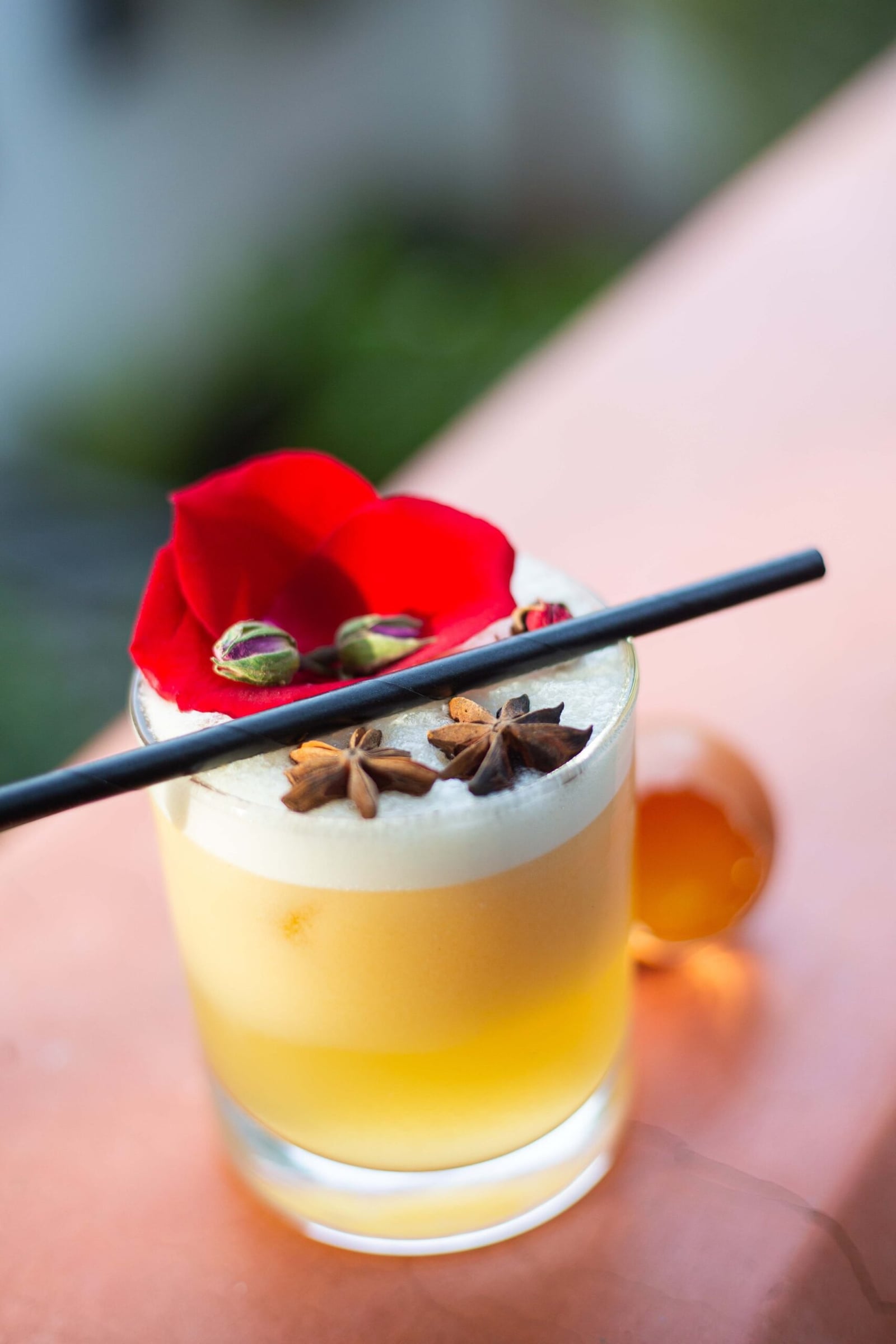 A frothy cocktail topped with a rose petal and star anise on the La Pergola rooftop
