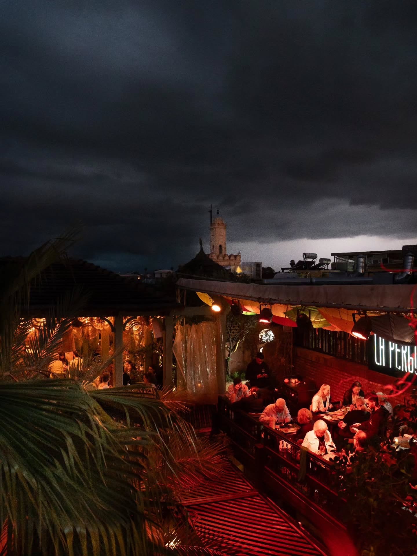 Storm clouds over the medina seen from La Pergola, diners on the lit terrace below