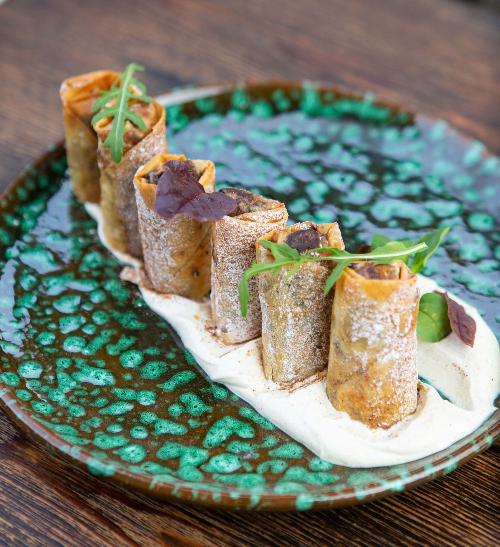 Rolled pastries on a green ceramic plate with cream, served at La Pergola