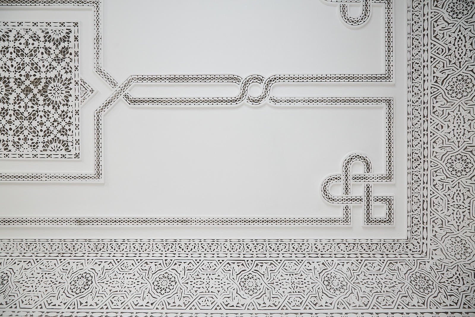 Hand-carved white plaster ceiling with geometric borders in a room at Numa Marrakech