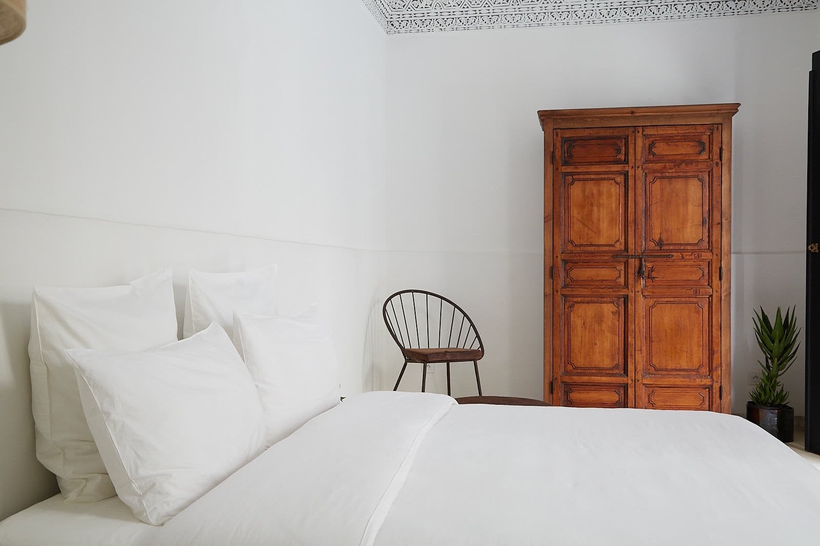 White double room at Numa Marrakech with a carved wooden wardrobe and a wire chair