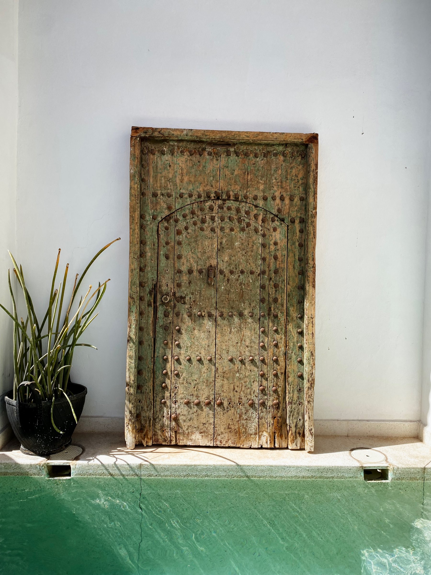 An antique carved door reflected in the water of the pool at Numa