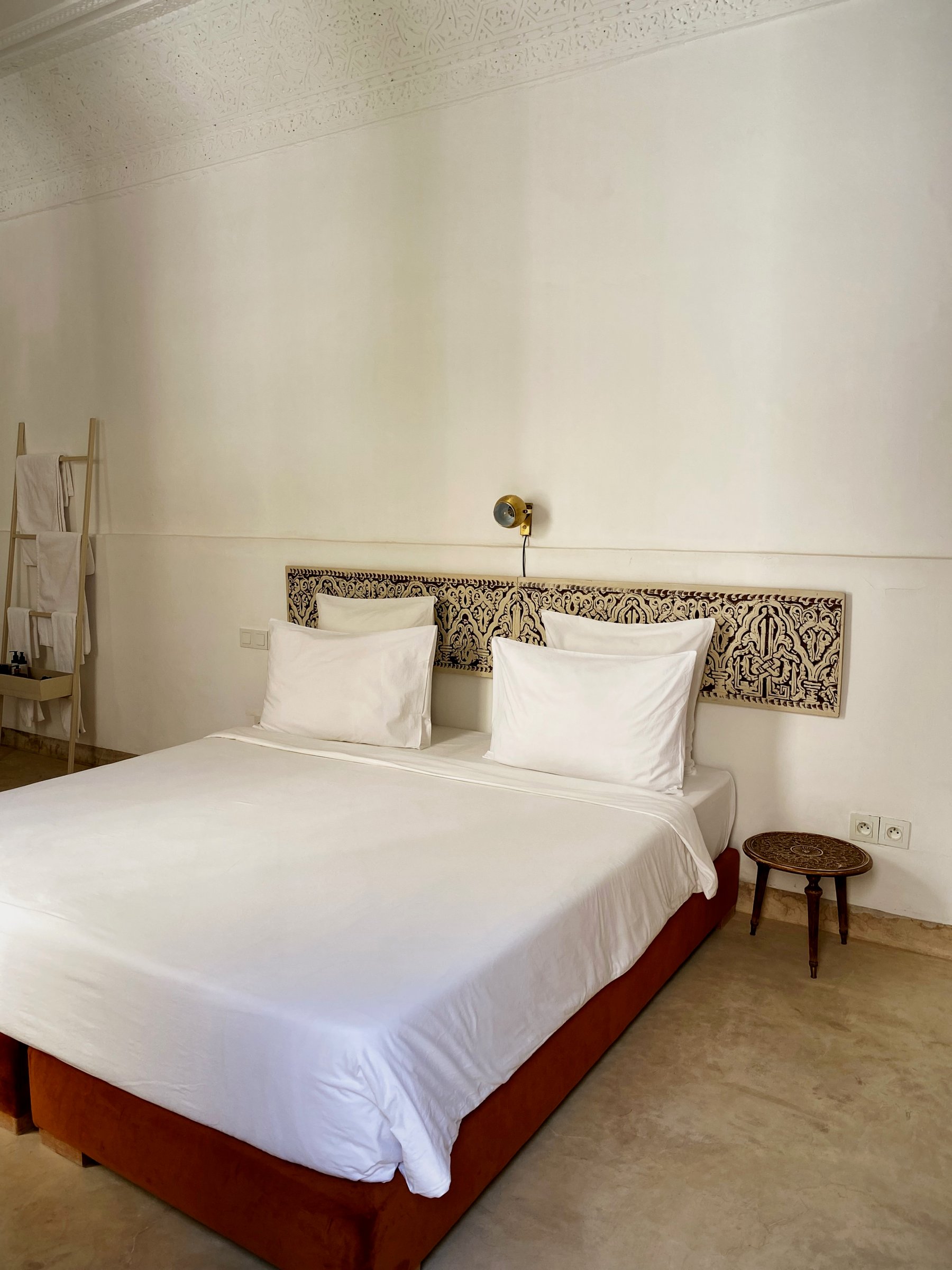 A white double bedroom at Numa with a carved wooden headboard panel