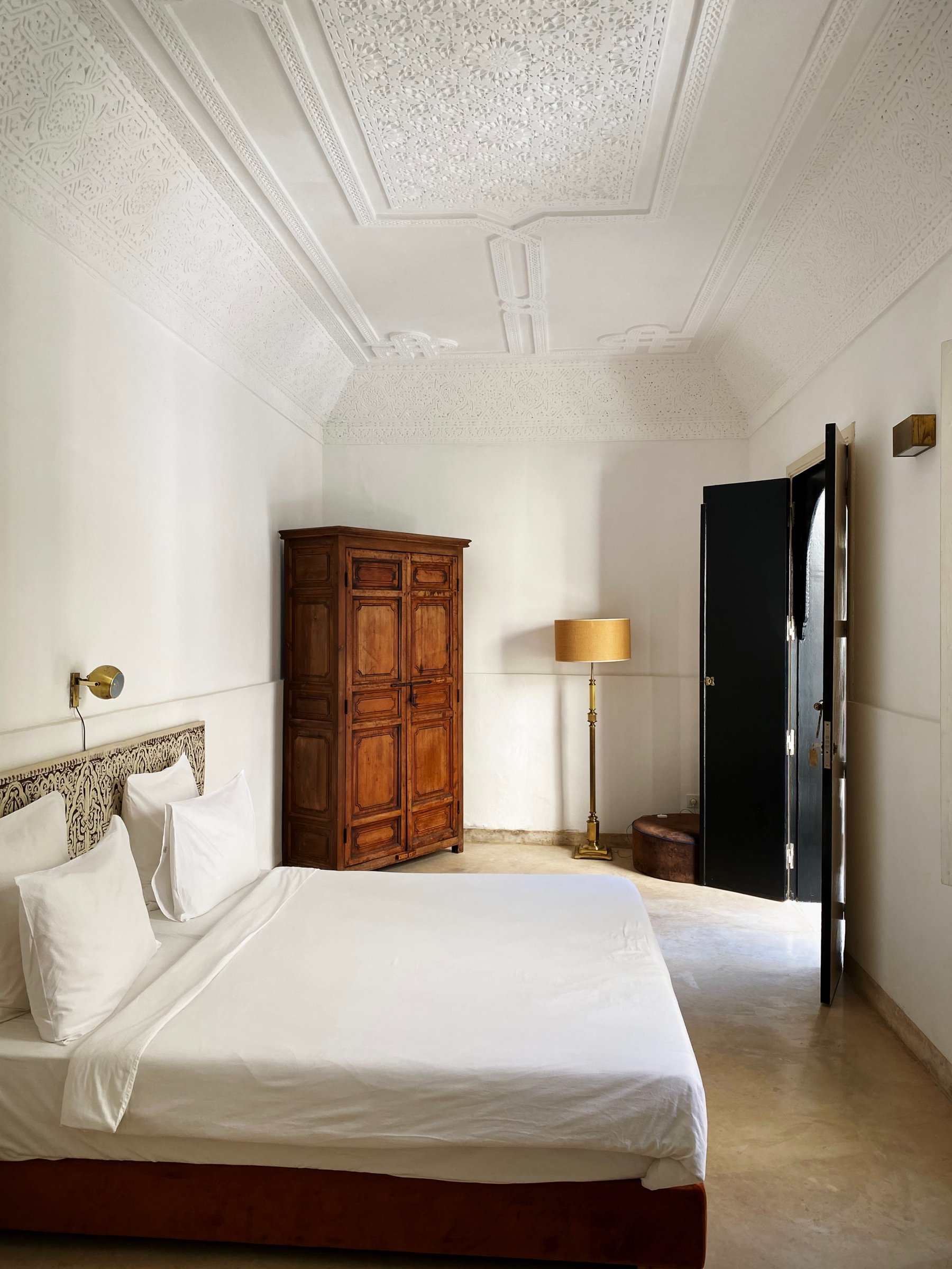 A bedroom at Numa with a carved plaster ceiling and an antique wooden wardrobe