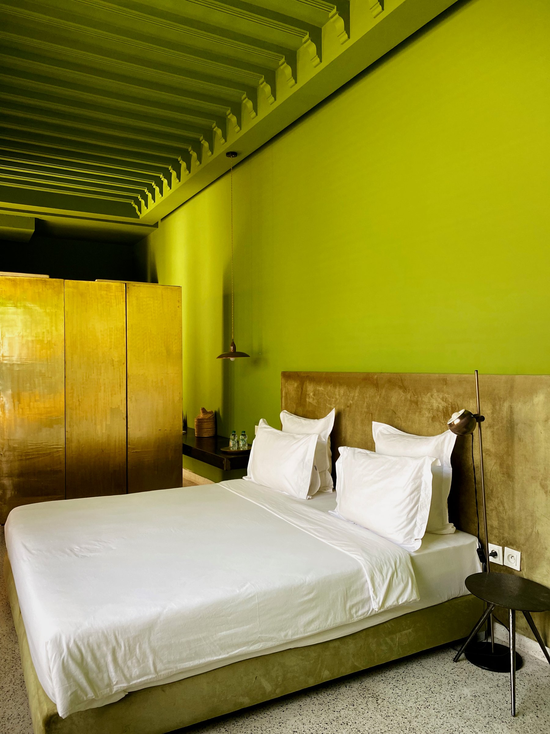 A bedroom at Numa with lime-green walls and a brass wardrobe
