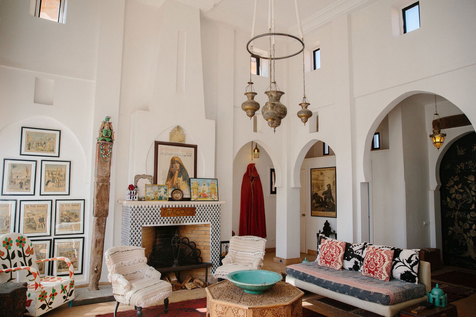 Medina Pavilion salon fireplace with a black-and-white zellige surround and a wooden PEACOCK sign above the hearth.