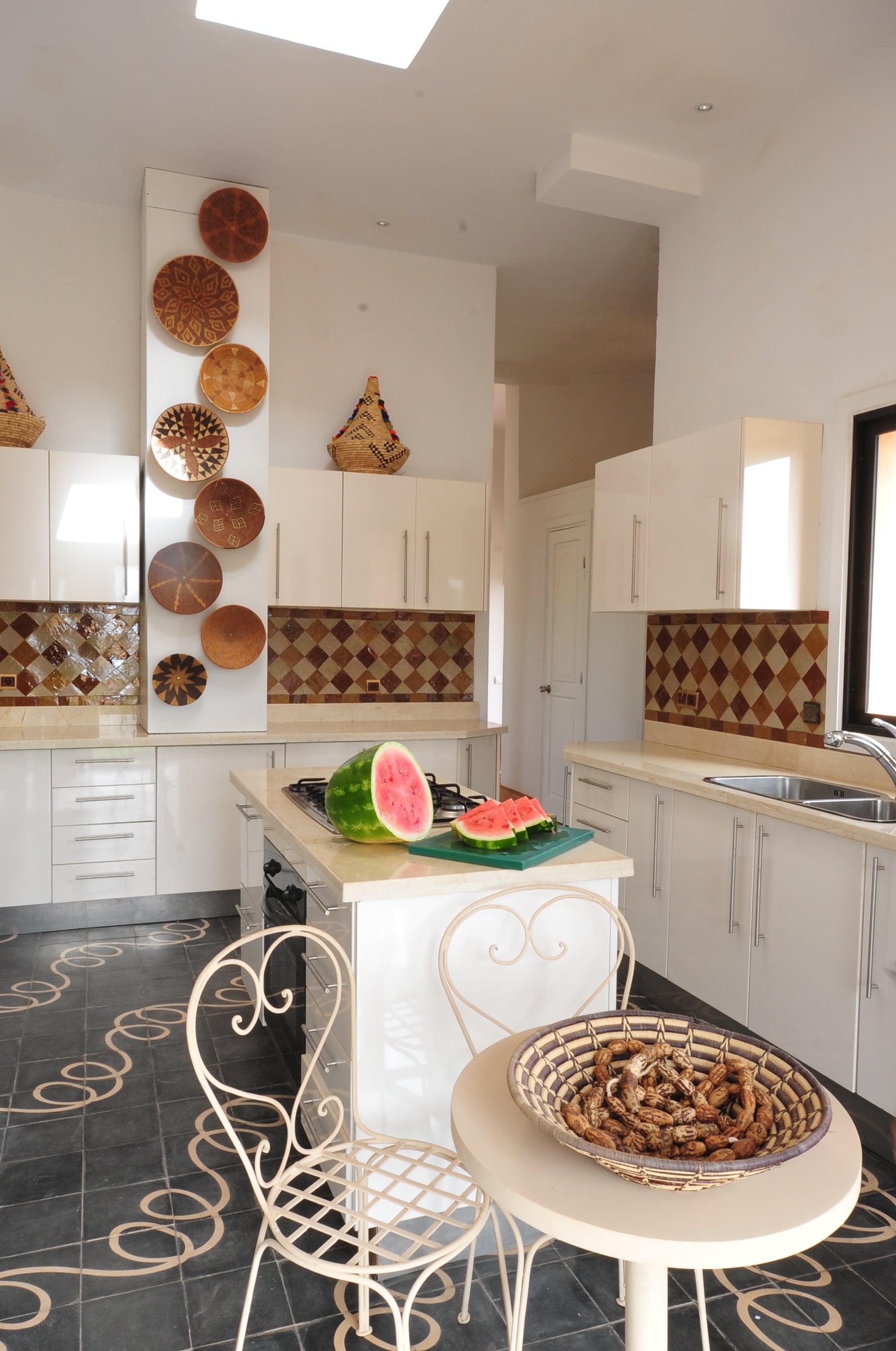 Medina Pavilion kitchen with a diamond-pattern glazed tile backsplash and a row of woven basket plates on the wall.