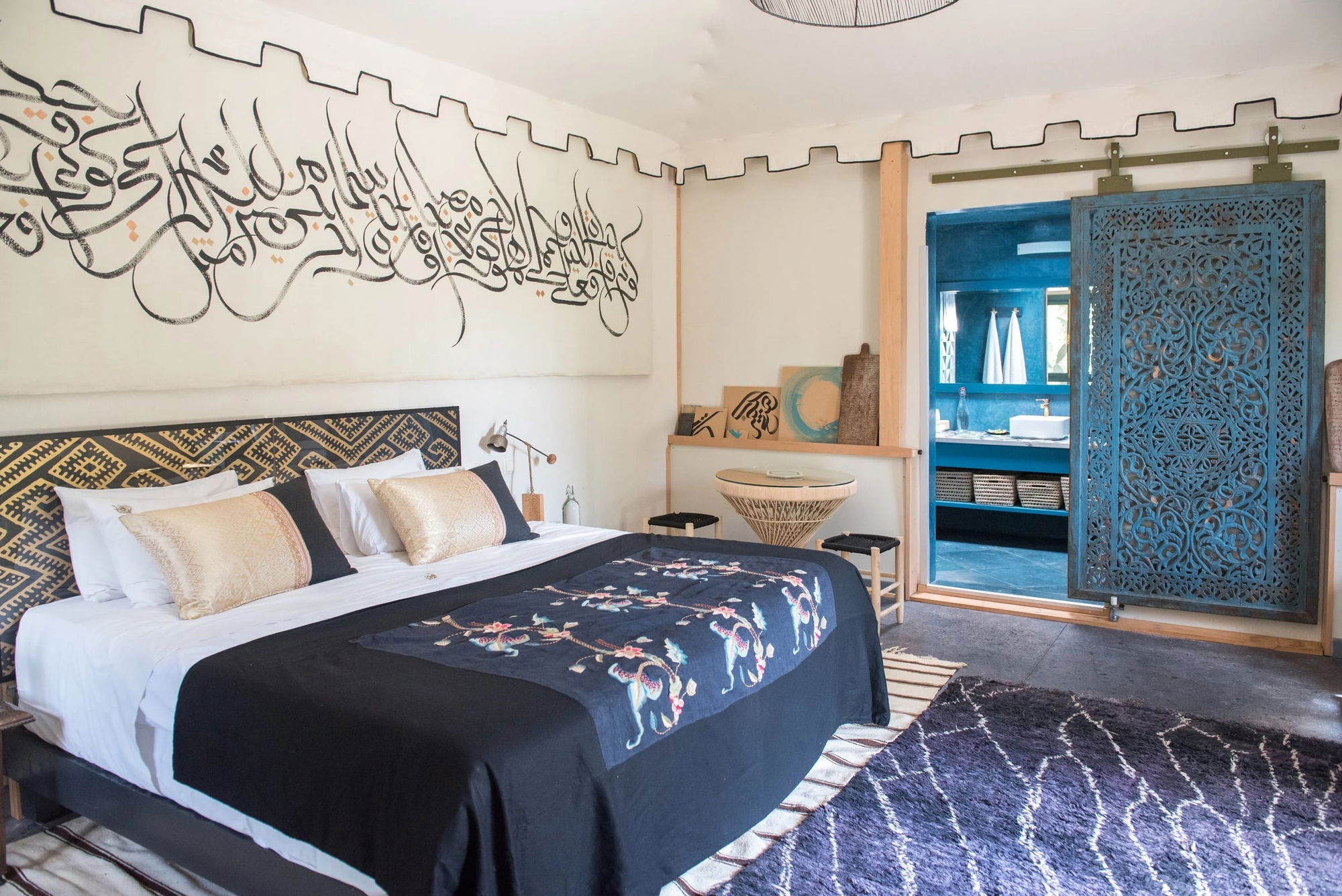 Bungalow Dawn Rising Room: black calligraphy mural above the bed, carved sliding door to the blue-tiled bathroom.