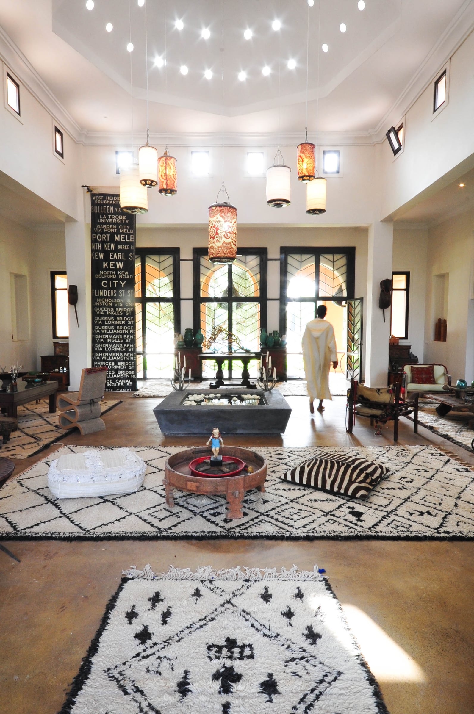 Main Pavilion entrance hall with a raised water basin, black-and-white Beni Ouarain rugs and a cluster of red lanterns.