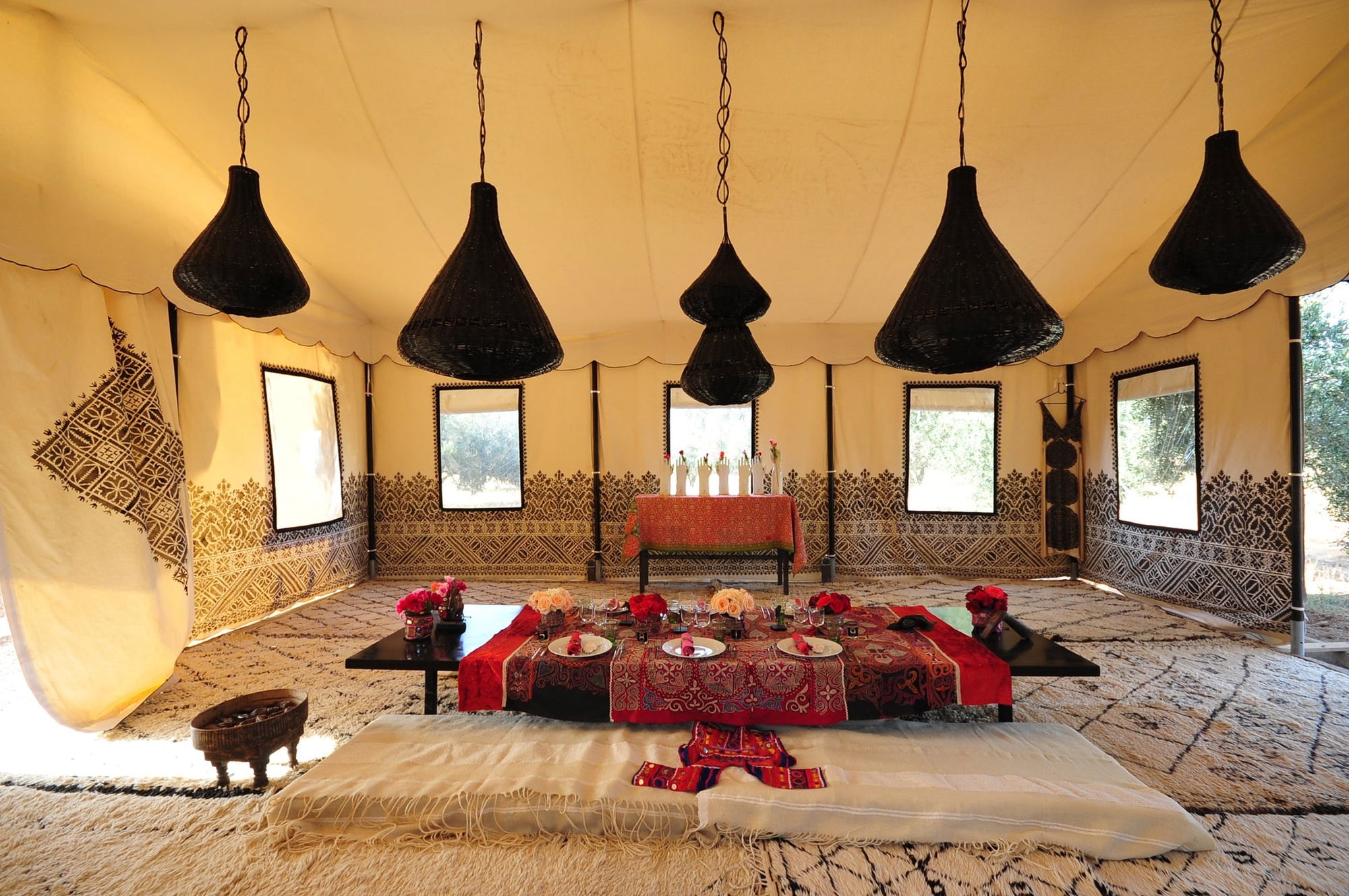 Arabian dining tent set for a long table, with dried olive branches hanging above and printed textile walls.