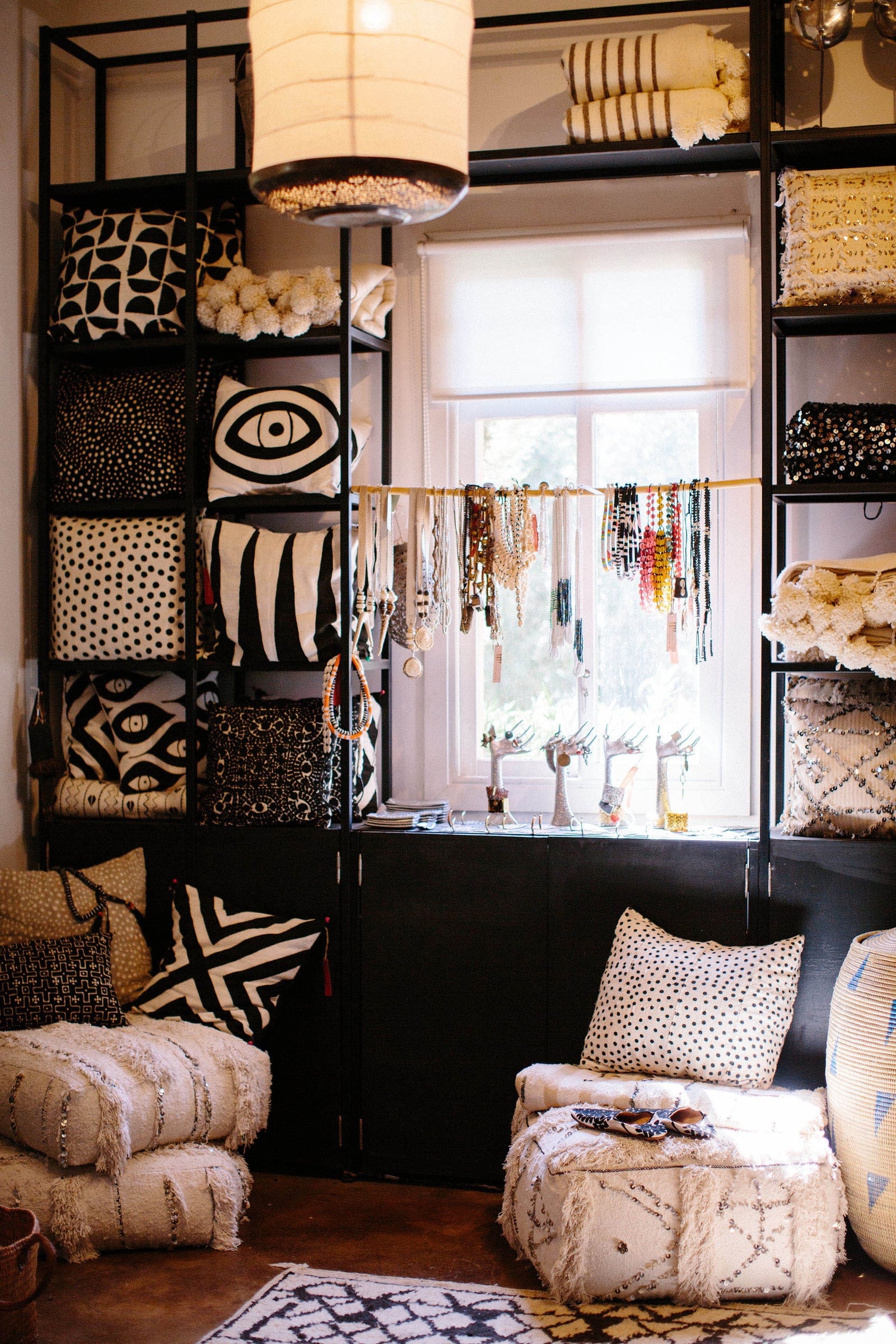 The Souk shop interior: shelves stacked with black-and-white printed cushions and beaded necklaces by a window.