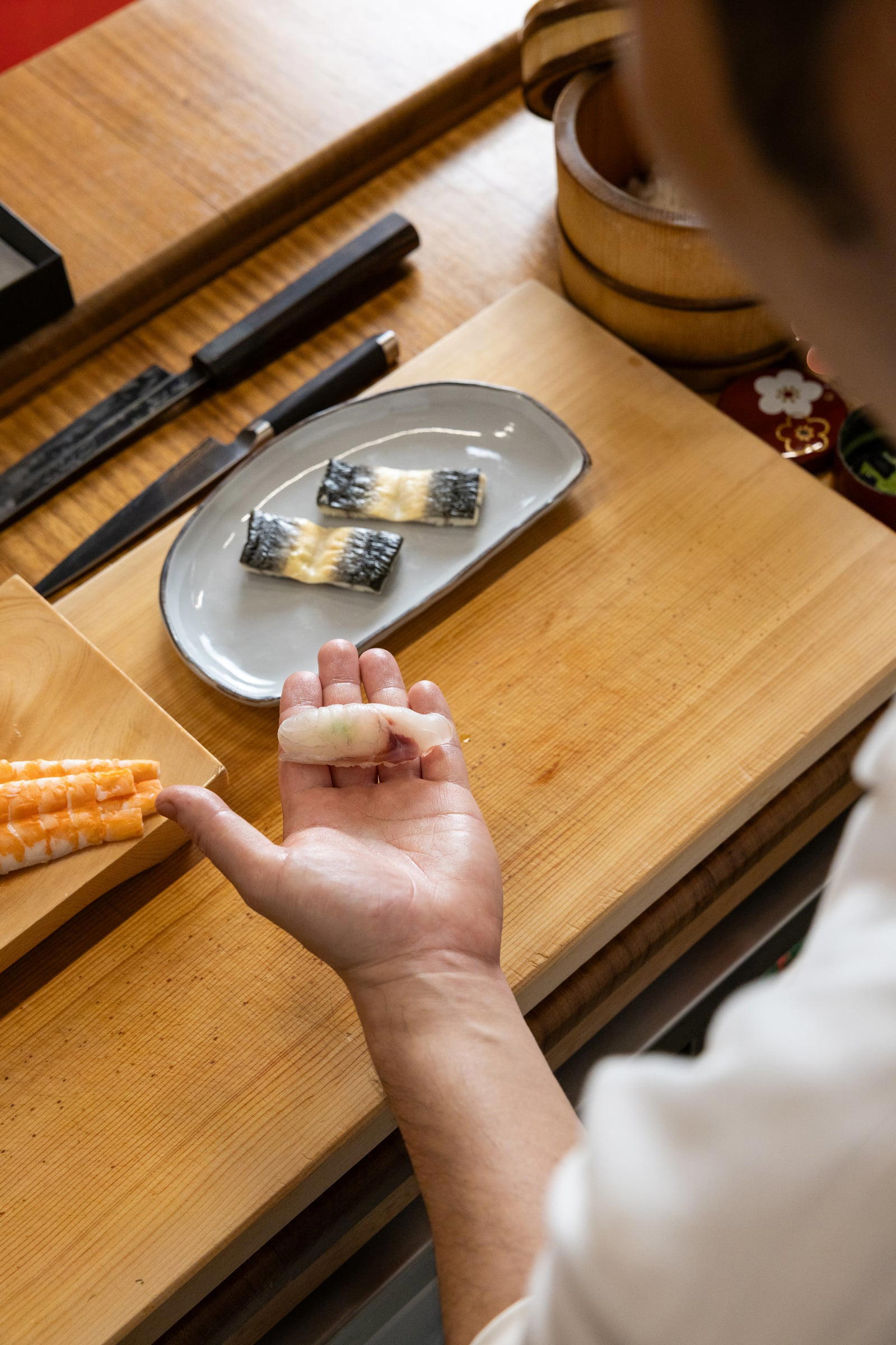 A piece of nigiri held in the chef's hand above the counter at IKI. Credit Joanne Poinsignon