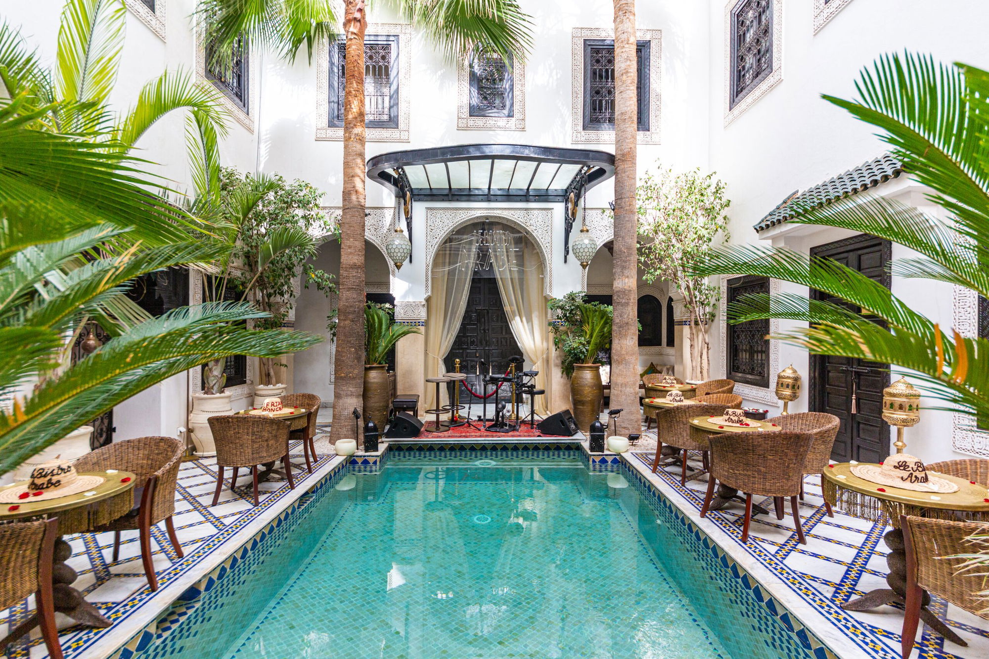 The courtyard of Riad Monceau, with its pool, palms and tables, below La Pergola