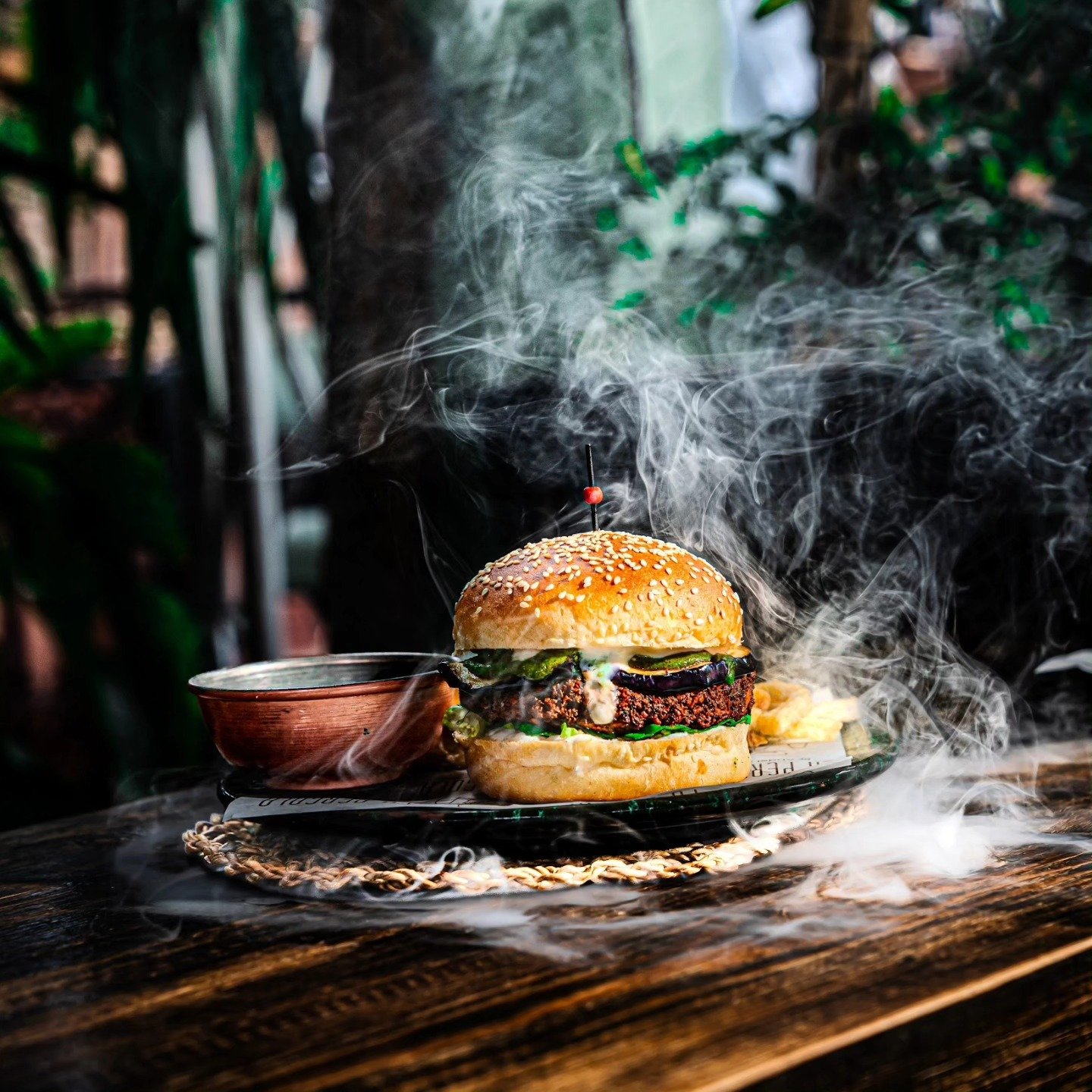 The La Pergola burger on a wooden board, with smoke rising behind it