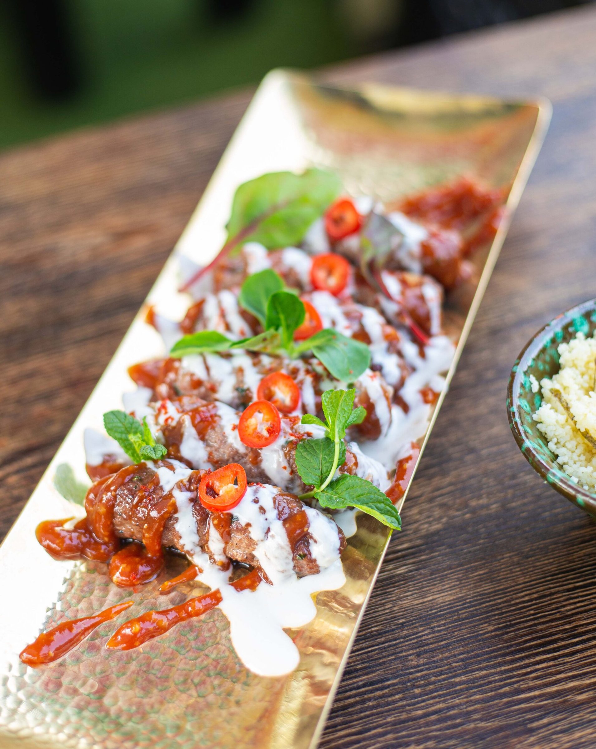 Grilled meat with chilli and yoghurt on a golden platter at La Pergola