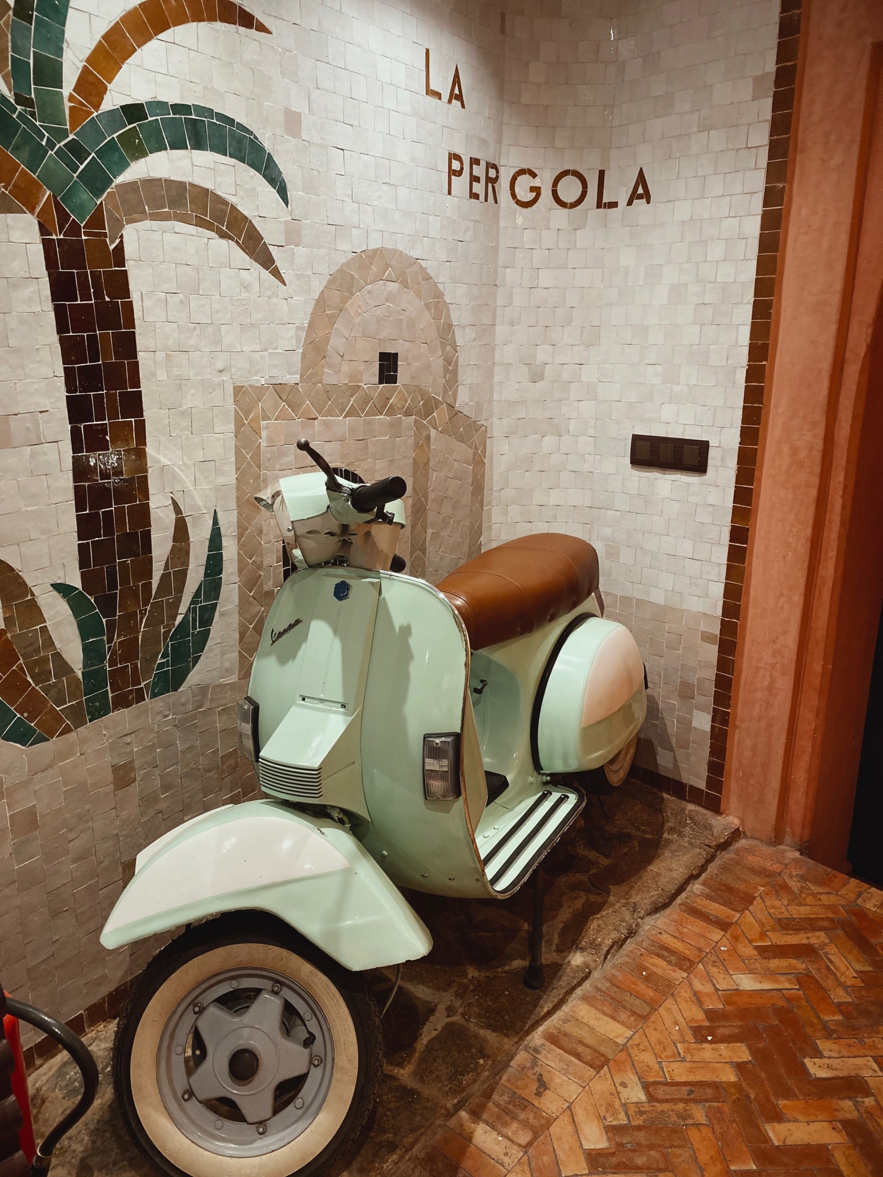 The mosaic La Pergola sign and a vintage Vespa at the entrance