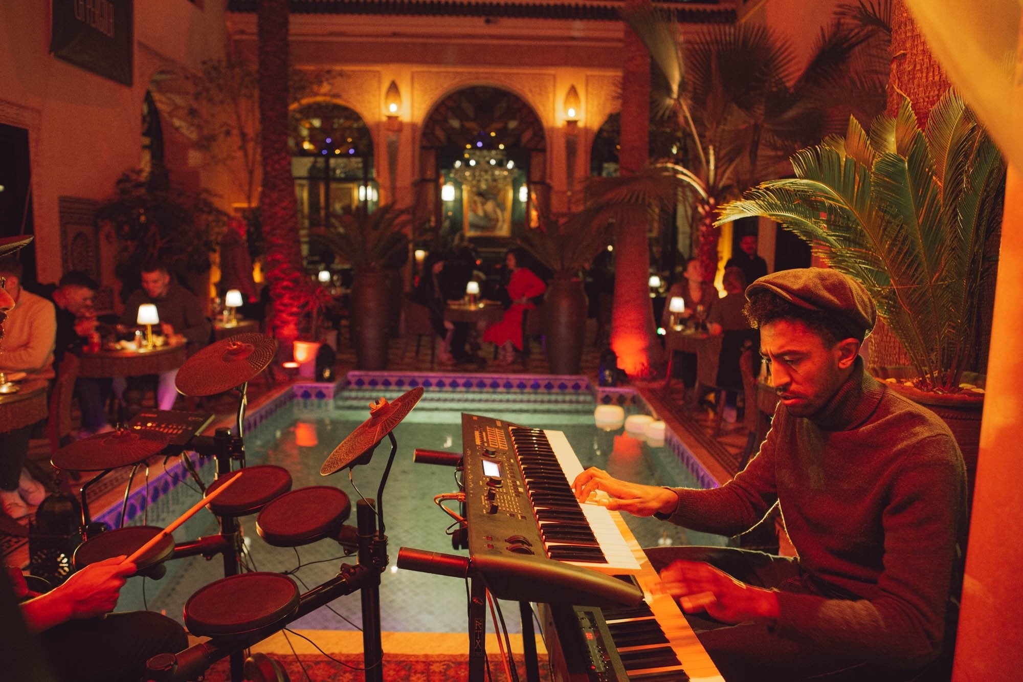 Pianist at a keyboard in the candlelit courtyard of Le Bistro Arabe, tables around the pool under palms and arches