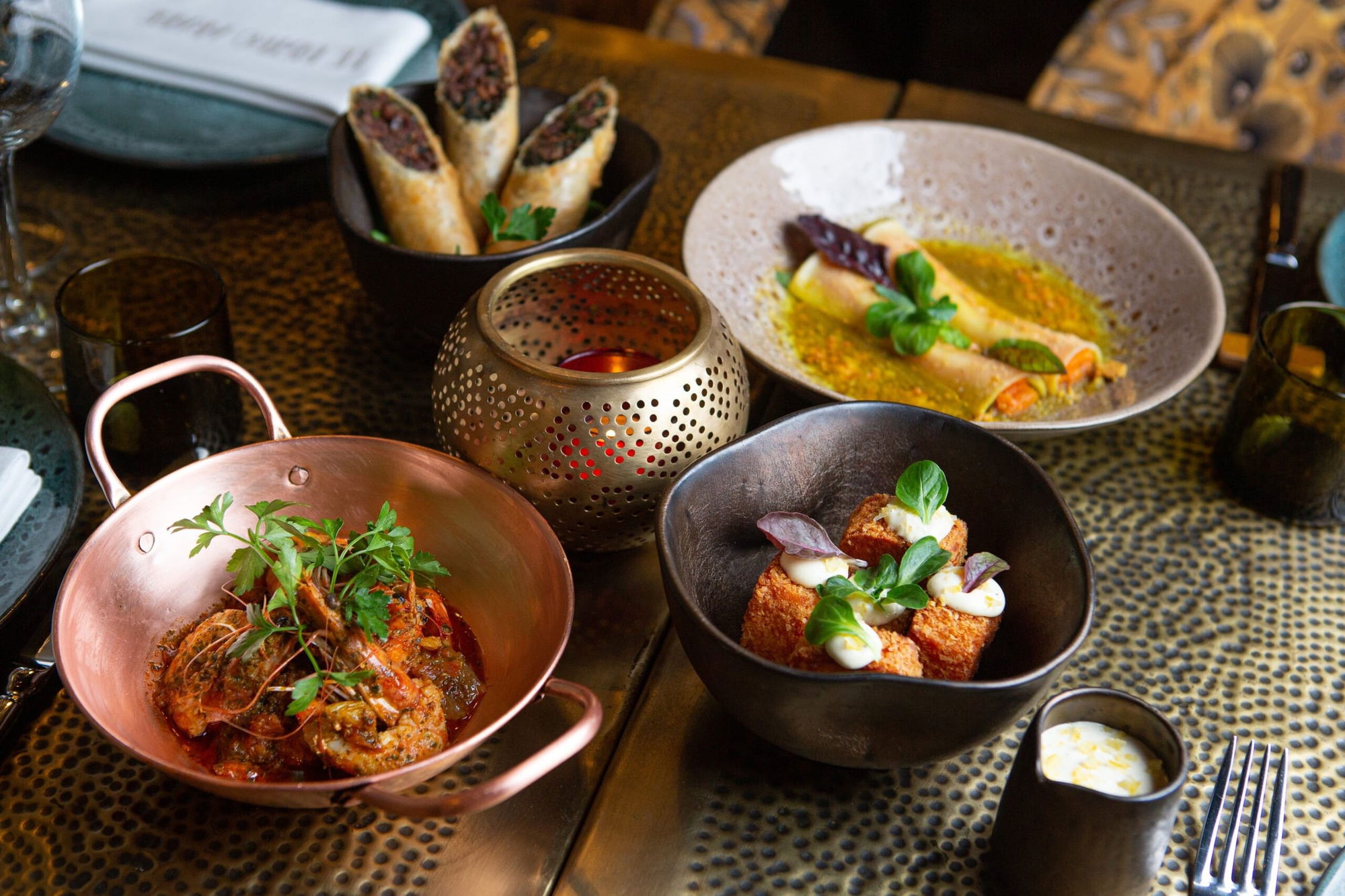 Dishes to share on a hammered brass table at Le Bistro Arabe, with a copper pan and a pierced brass lantern
