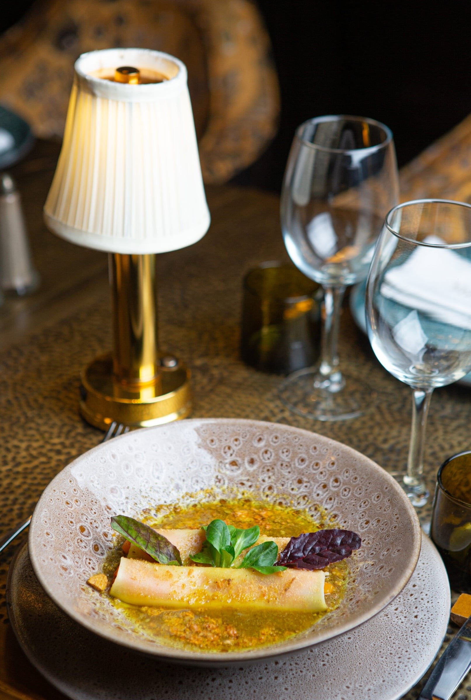 Pasta parcels in a golden broth at Le Bistro Arabe, served beside a small brass table lamp