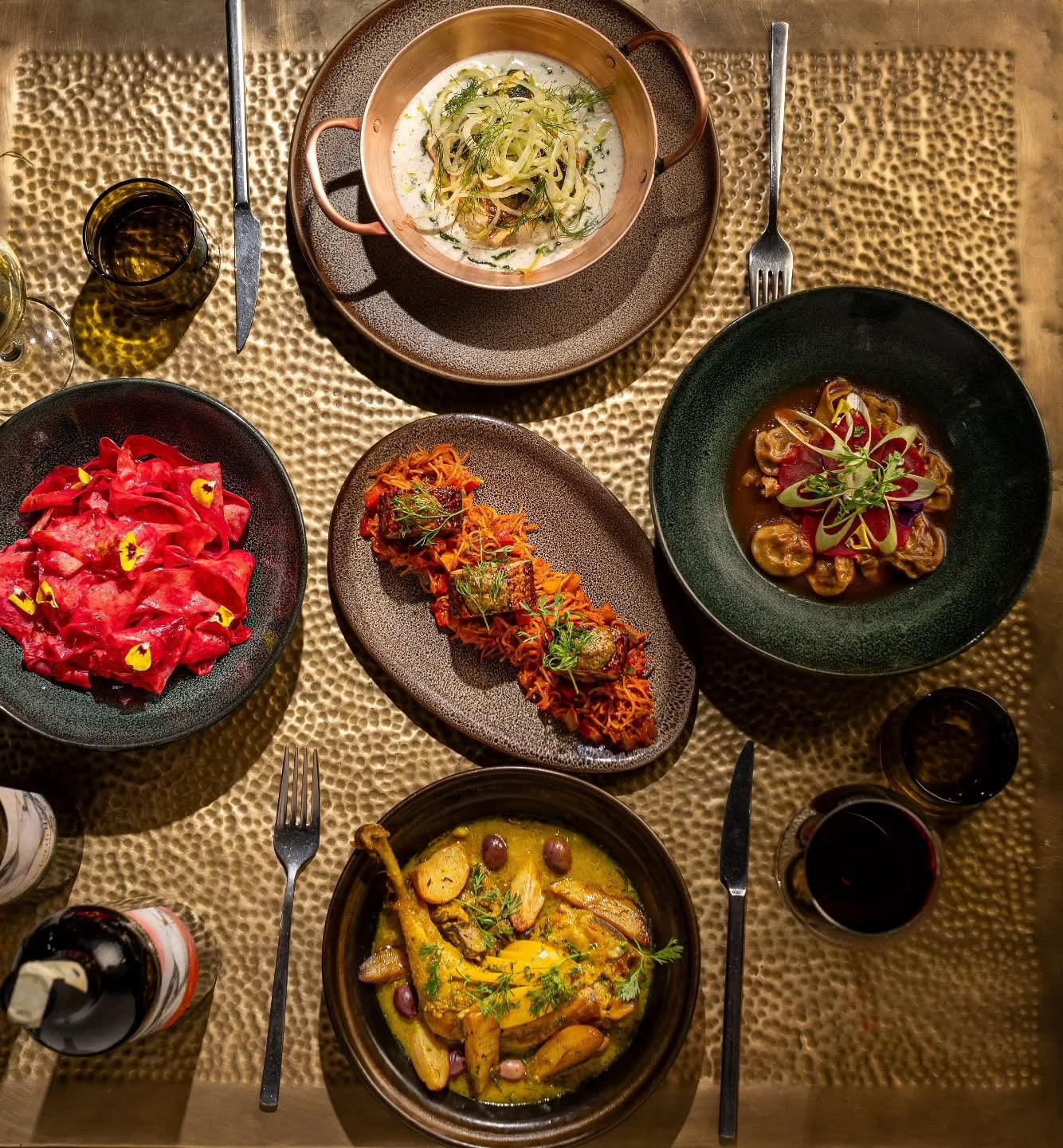 Shared dishes seen from above on a brass table at Le Bistro Arabe, from chicken with olives to beetroot