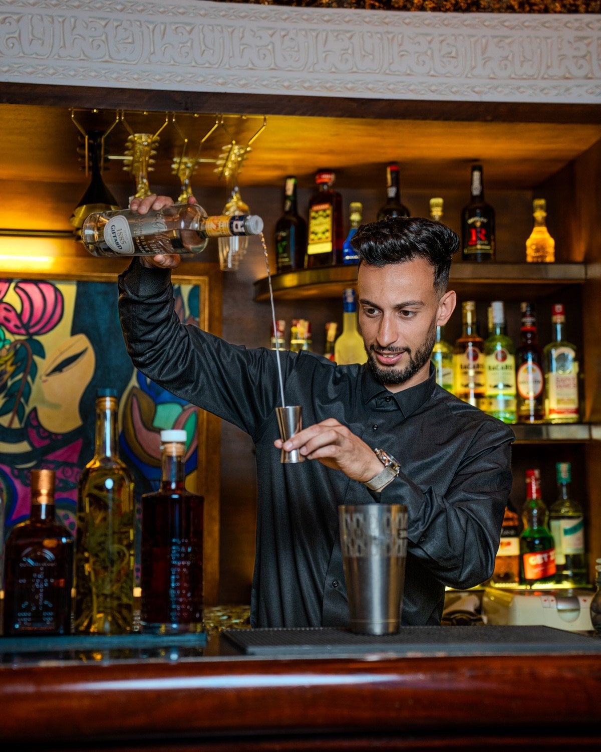 Bartender pouring a measure behind the bar of Caravan, the cocktail bar of Le Bistro Arabe