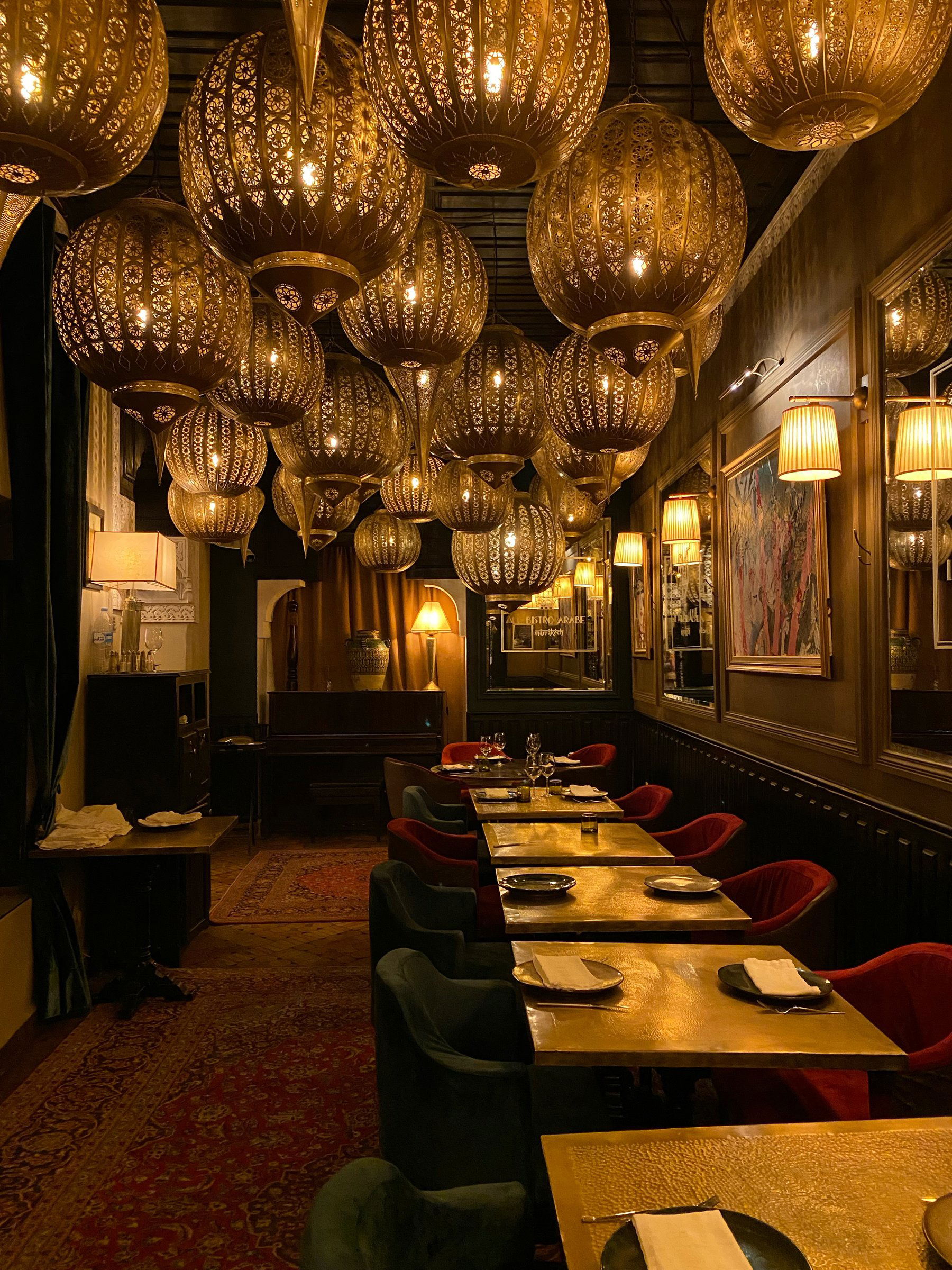 The dining room under a ceiling of hanging brass lanterns, with red velvet chairs