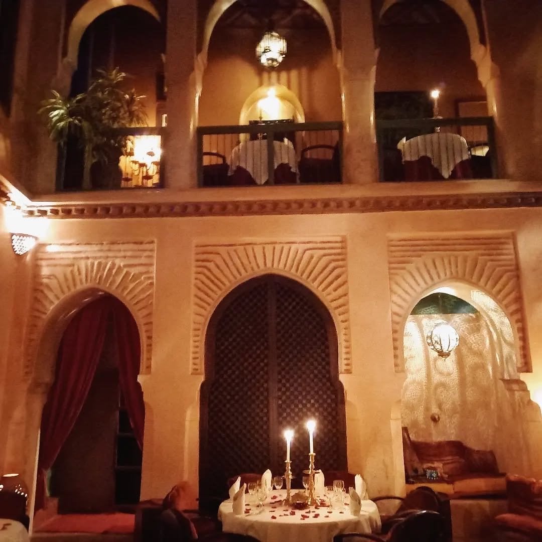 The two-level courtyard of Le Tobsil at night, a candlelit table below and dining balconies above