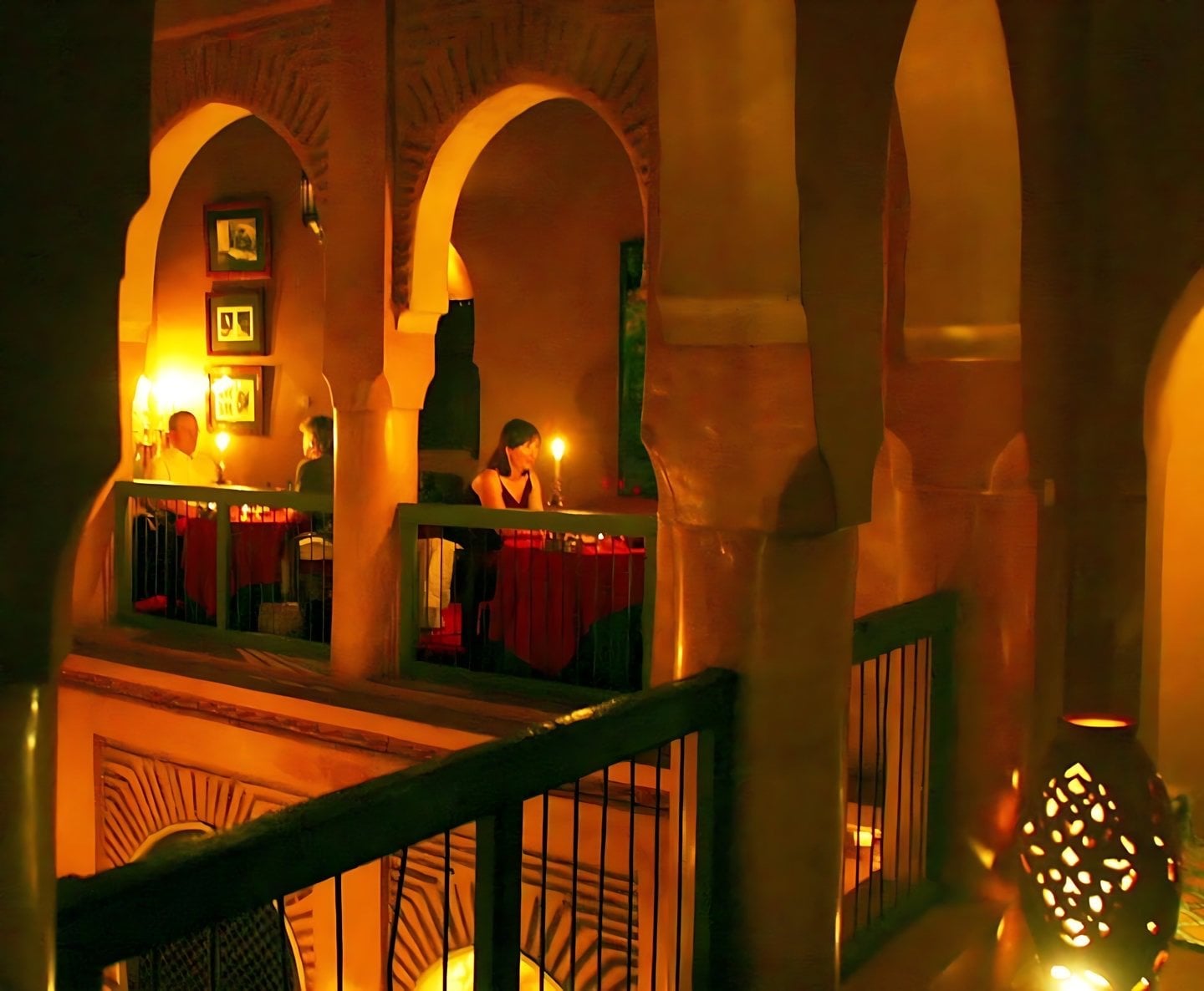 Guests dining by candlelight on the first-floor gallery of Le Tobsil, between arches above the courtyard