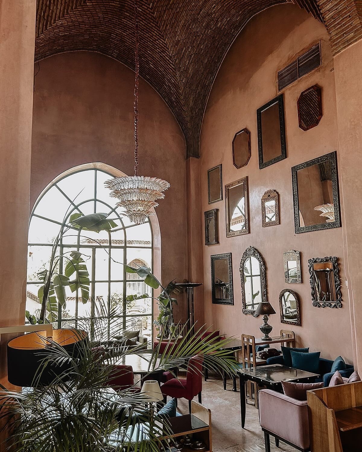 Salammbô's dining room at Les Deux Tours, with a high vaulted ceiling, an arched window and a wall of framed mirrors