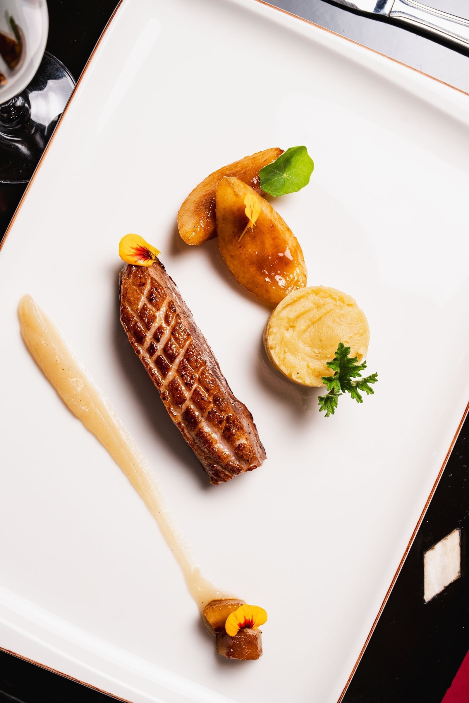Sliced duck breast with roasted fruit, a potato cake and a swirl of purée, plated at Salammbô