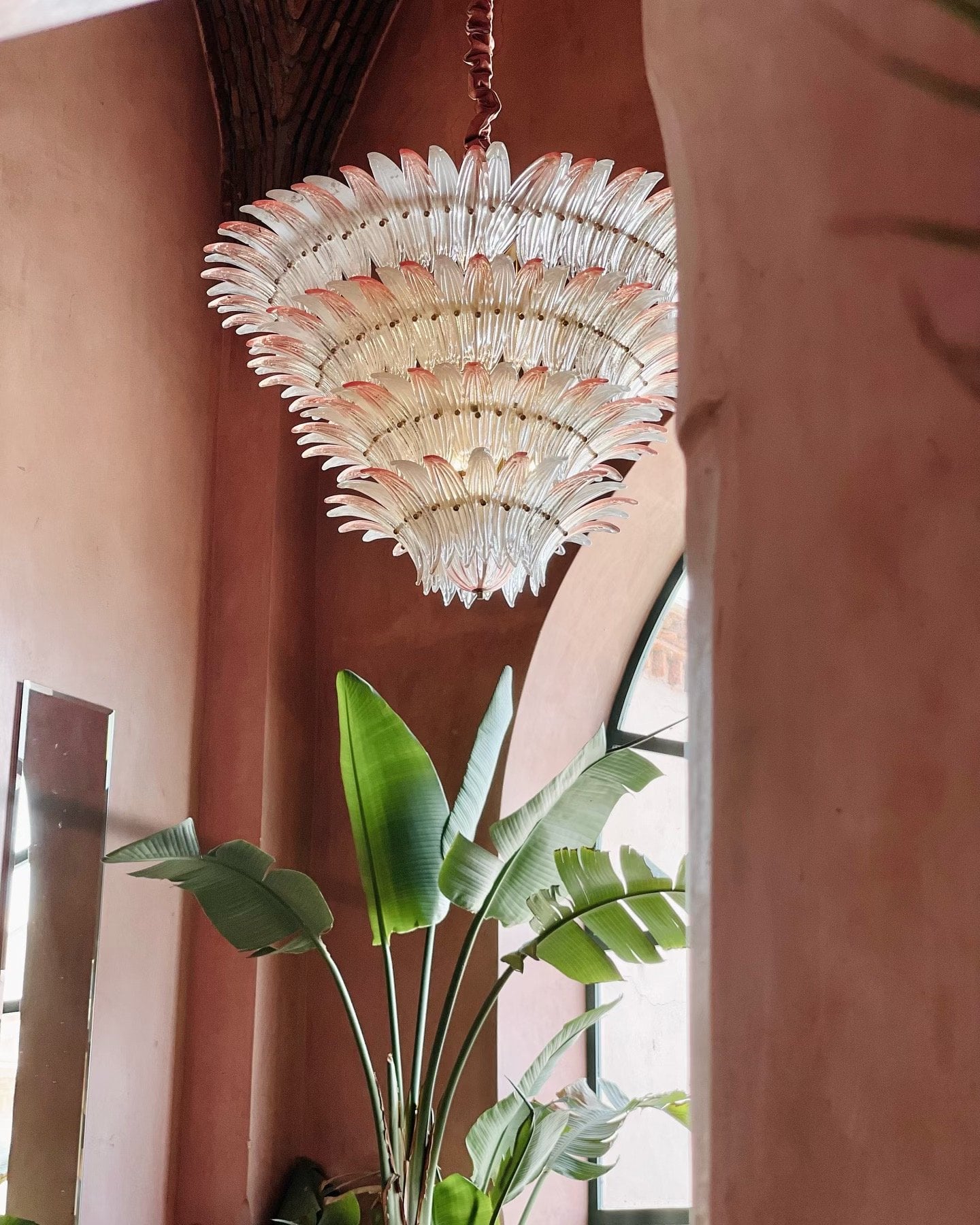 A white glass chandelier hanging against the pink walls of Salammbô's dining room at Les Deux Tours