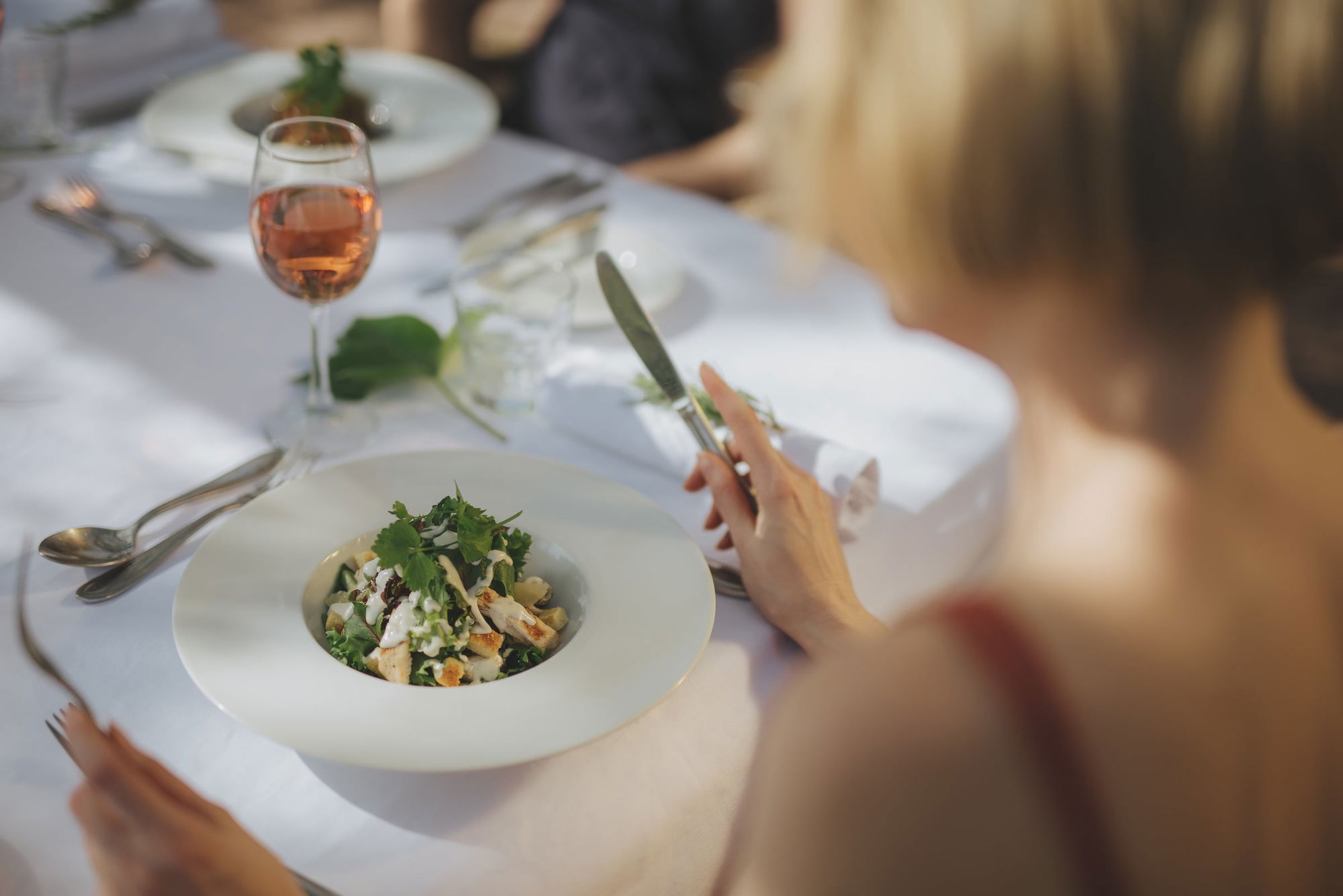 A guest dining on the terrace of Salammbô with a salad and a glass of rosé